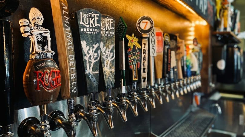 A row of beer taps with various branded handles, including "Rogue" and "Lucky Luke".