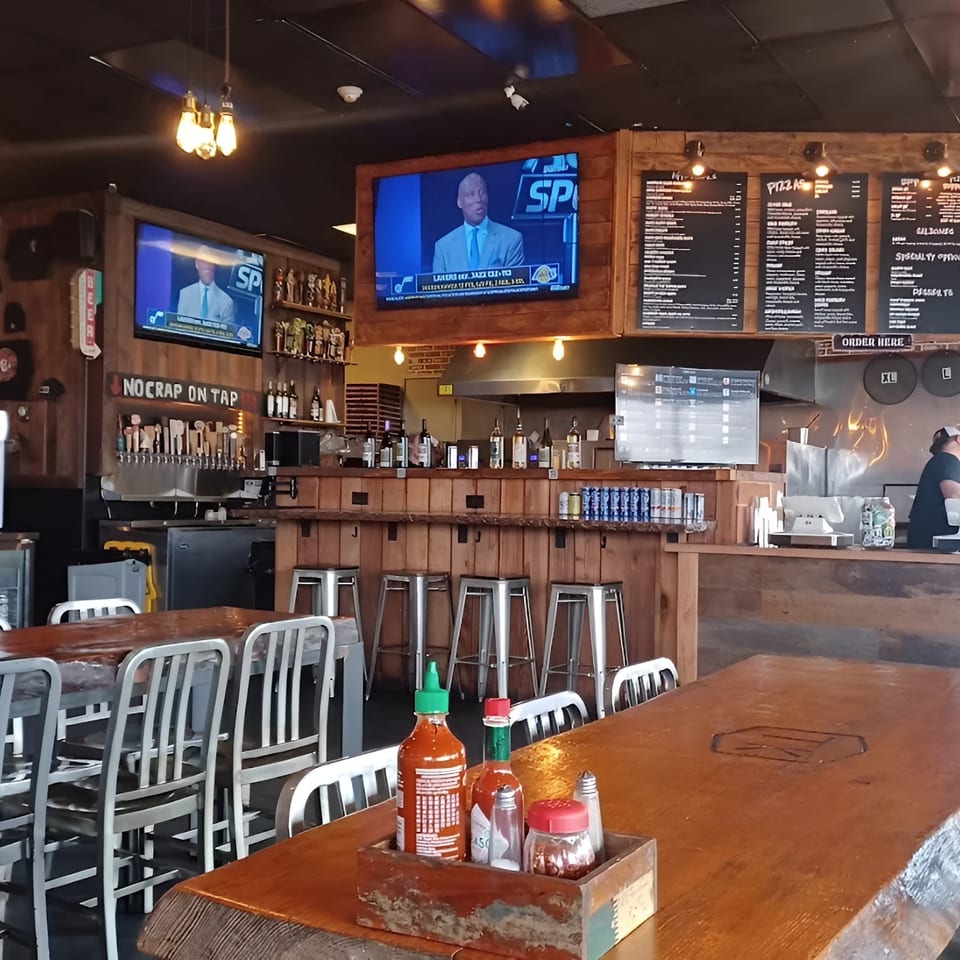 Interior of TK Pizza and Pasta, showing dining tables, a bar with taps, and a counter.