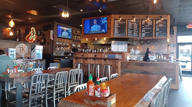 Interior of TK Pizza and Pasta, showing dining tables, a bar with taps, and a counter.