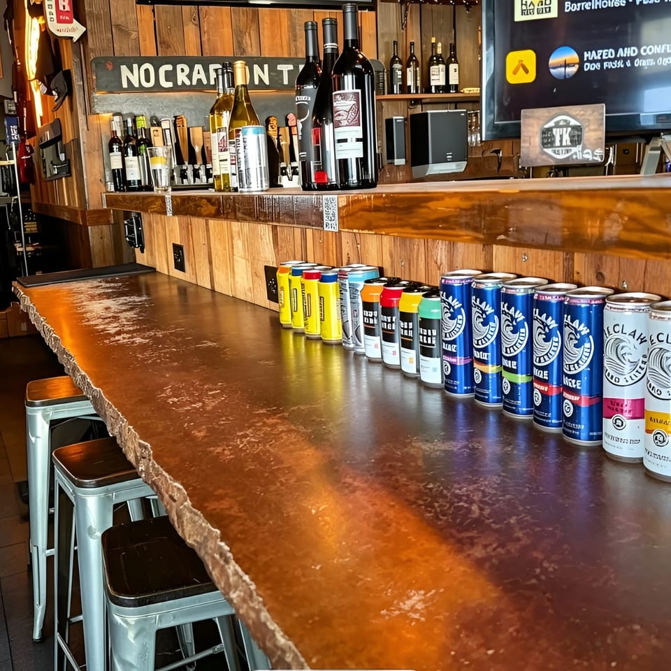 A rustic bar with a live-edge wooden counter, lined with various canned beverages and bar stools.